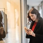 close up photo of woman in black coat using smartphone