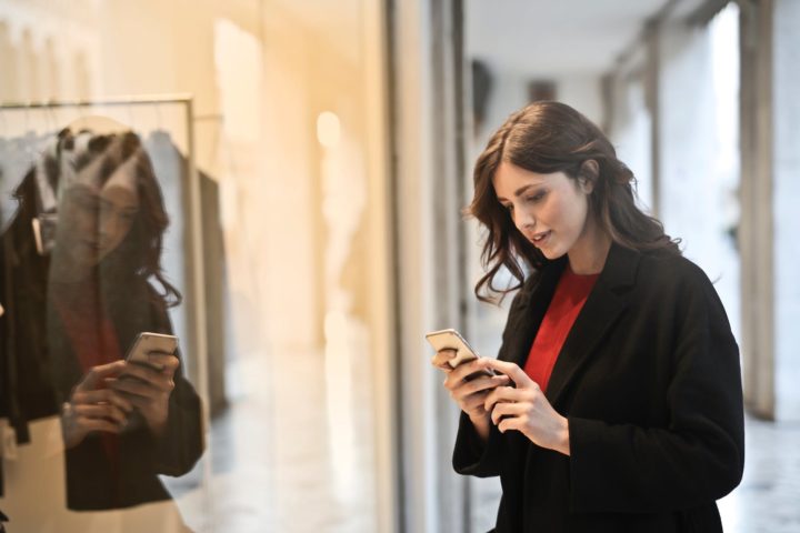 close up photo of woman in black coat using smartphone